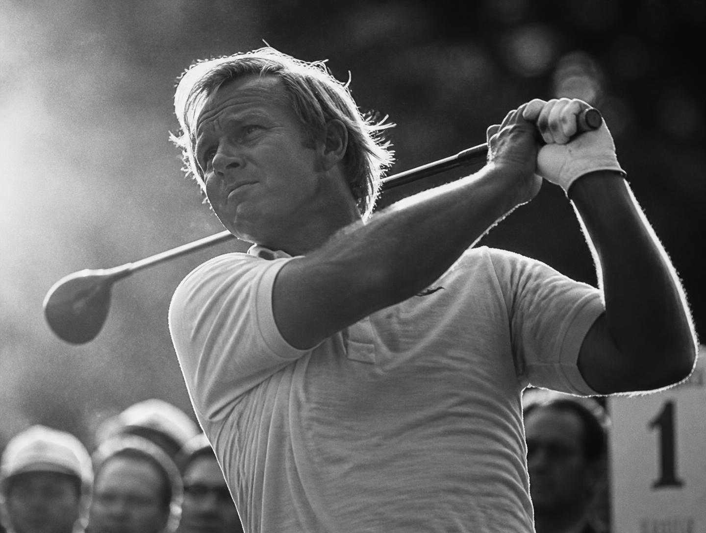 Golfer mid-swing at the first tee in black and white